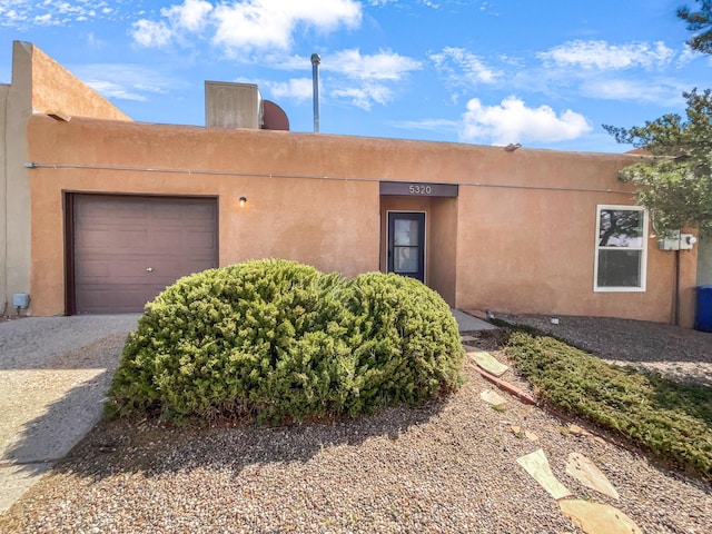 pueblo-style home featuring stucco siding and a garage