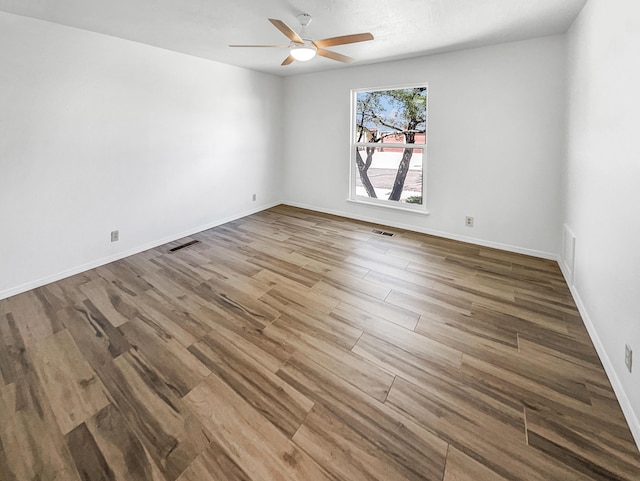 spare room with visible vents, baseboards, ceiling fan, and wood finished floors