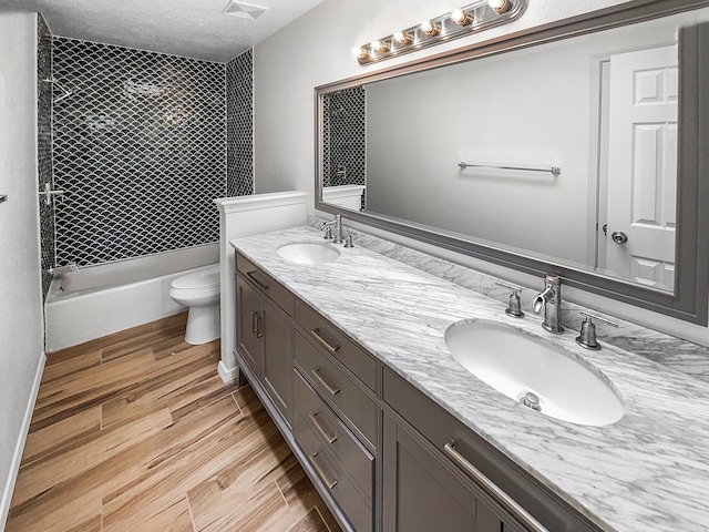 full bathroom with double vanity, toilet, wood finished floors, and a sink