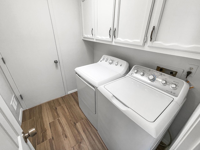 laundry room with cabinet space, dark wood-style floors, and washing machine and clothes dryer