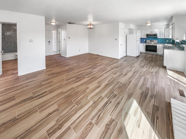 kitchen with tasteful backsplash, light wood finished floors, open floor plan, and appliances with stainless steel finishes