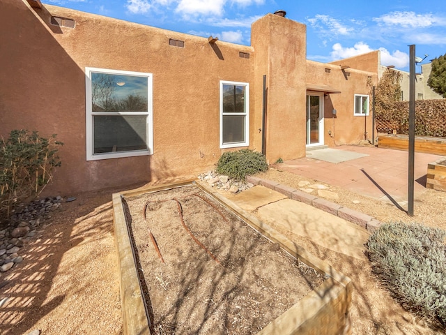 rear view of property featuring a patio, fence, and stucco siding