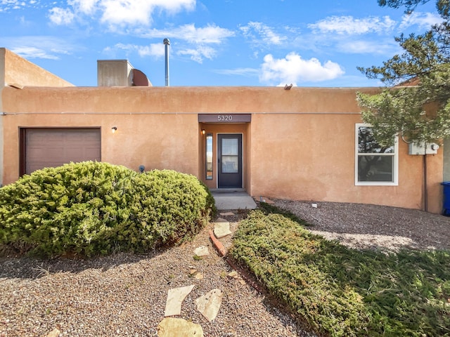 entrance to property featuring an attached garage and stucco siding