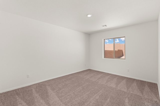 carpeted spare room with visible vents and baseboards