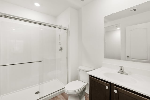 bathroom with vanity, wood finished floors, visible vents, a stall shower, and toilet