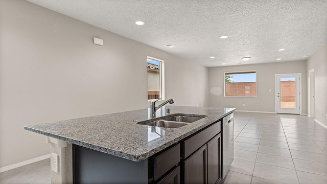 kitchen featuring a sink, baseboards, stainless steel dishwasher, and a center island with sink