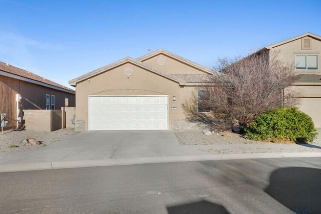 view of front of home with a garage, concrete driveway, fence, and stucco siding