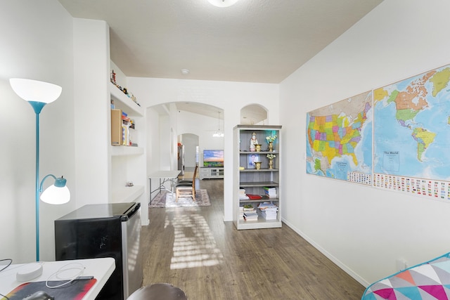 hallway featuring baseboards, arched walkways, and wood finished floors