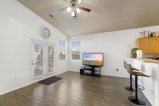 living room featuring baseboards, visible vents, vaulted ceiling, and dark wood-style flooring