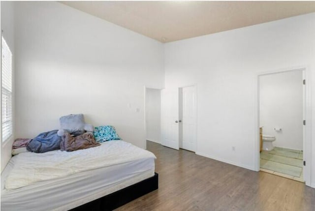 bedroom featuring ensuite bath and wood finished floors