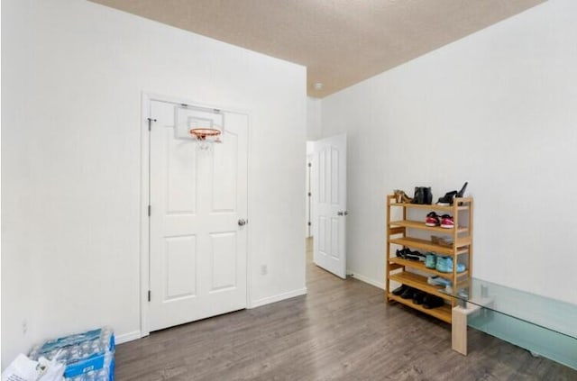 interior space with a textured ceiling, wood finished floors, and baseboards