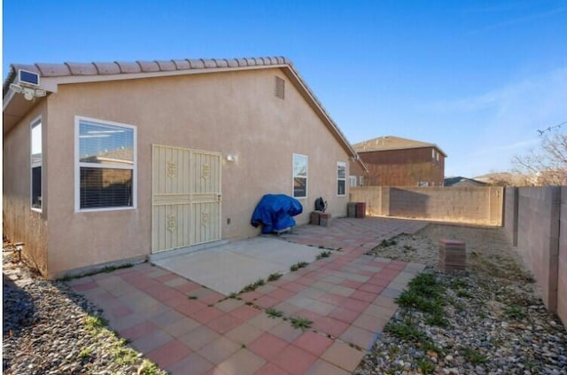 back of property with a fenced backyard, a tiled roof, a patio, and stucco siding