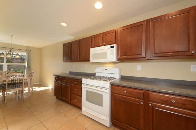 kitchen with dark countertops, light tile patterned floors, recessed lighting, and white appliances