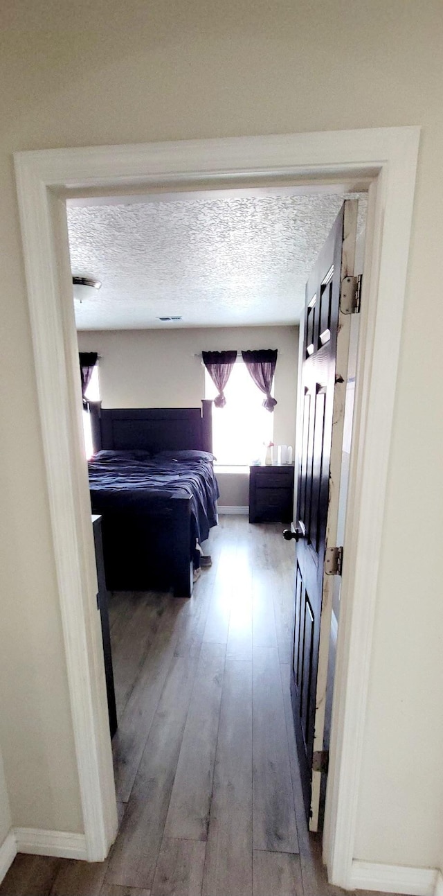 bedroom featuring baseboards, a textured ceiling, and hardwood / wood-style flooring