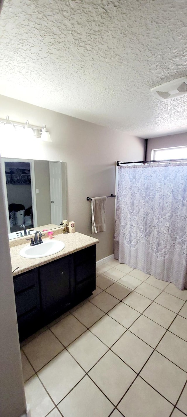 full bathroom with tile patterned floors, curtained shower, a textured ceiling, and vanity