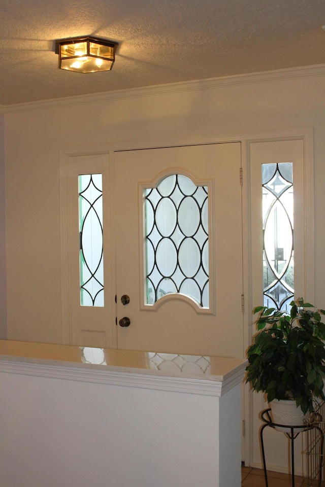 entryway featuring a healthy amount of sunlight, crown molding, and a textured ceiling