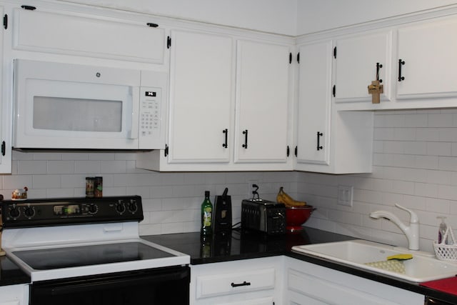 kitchen featuring white microwave, range with electric stovetop, a sink, white cabinetry, and backsplash