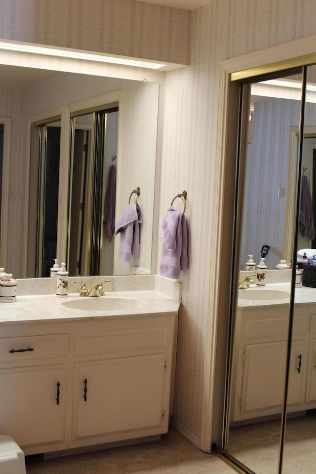 bathroom featuring wallpapered walls and vanity