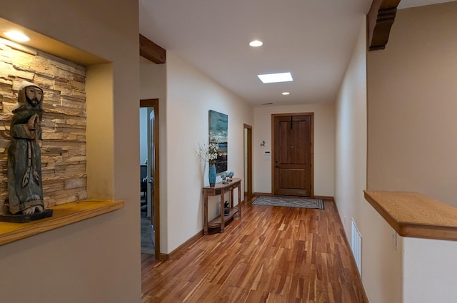 corridor featuring recessed lighting, visible vents, baseboards, and wood finished floors