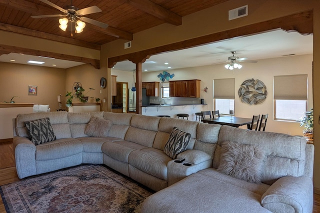 living area with visible vents, ceiling fan, beamed ceiling, wood ceiling, and wood finished floors