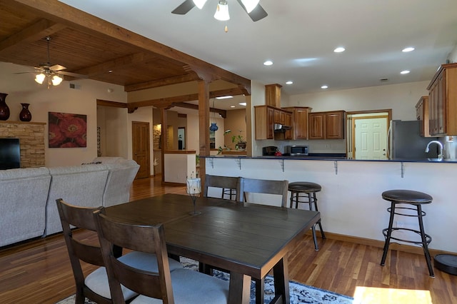 dining space with beam ceiling, visible vents, a ceiling fan, and wood finished floors