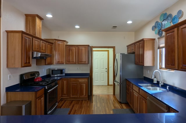 kitchen with wood finished floors, visible vents, a sink, stainless steel appliances, and under cabinet range hood