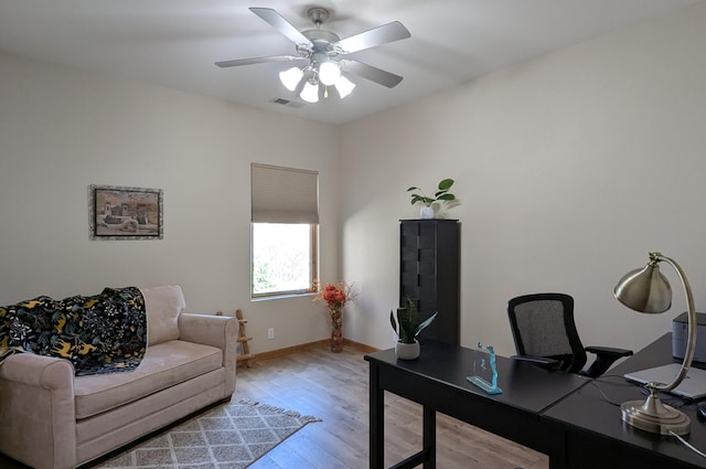 office space with baseboards, light wood-style floors, visible vents, and ceiling fan