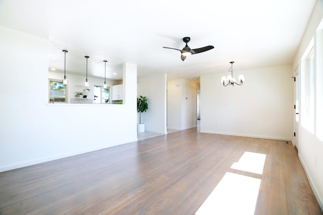 unfurnished living room featuring ceiling fan with notable chandelier, recessed lighting, wood finished floors, and baseboards