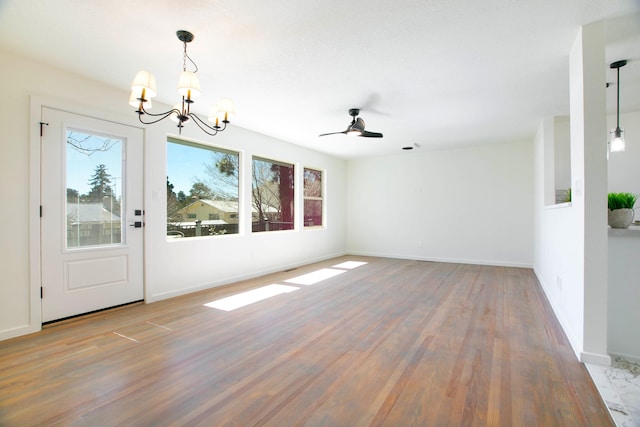 interior space featuring ceiling fan with notable chandelier, wood finished floors, and baseboards