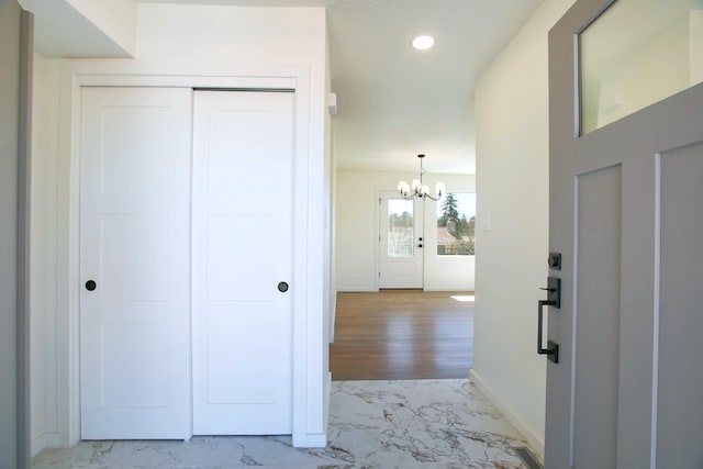 foyer featuring baseboards, recessed lighting, an inviting chandelier, marble finish floor, and a textured ceiling