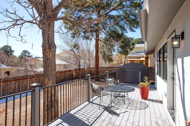 wooden deck featuring an outbuilding, a storage unit, and a fenced backyard