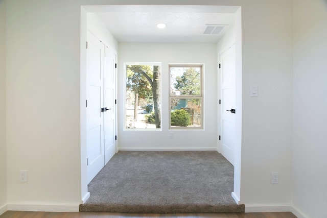 doorway to outside with visible vents, baseboards, and carpet flooring