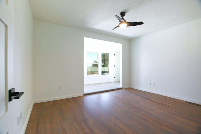 empty room featuring a ceiling fan, baseboards, visible vents, dark wood-type flooring, and a textured ceiling