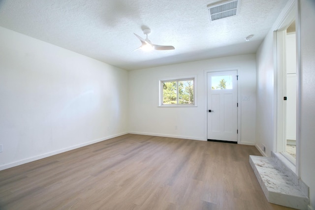 interior space featuring visible vents, baseboards, a textured ceiling, and wood finished floors