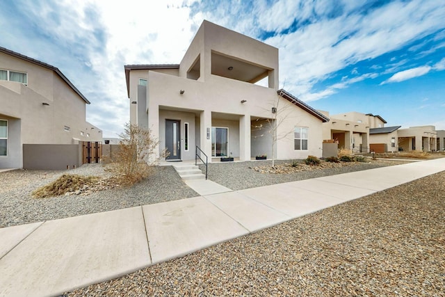 view of front facade with stucco siding and fence