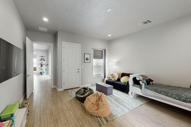 bedroom with light wood-style flooring, recessed lighting, visible vents, and a textured ceiling