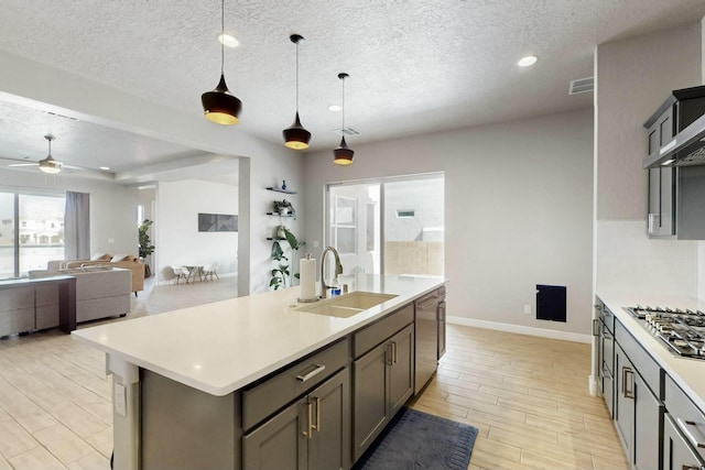 kitchen with appliances with stainless steel finishes, light countertops, wood finish floors, and a sink