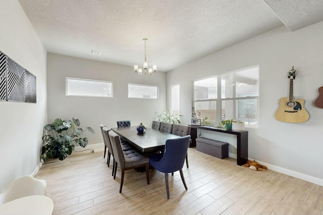 dining area featuring a textured ceiling, visible vents, light wood-type flooring, and a chandelier