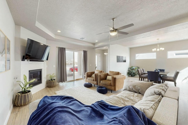 living area featuring visible vents, wood finished floors, a textured ceiling, and a glass covered fireplace