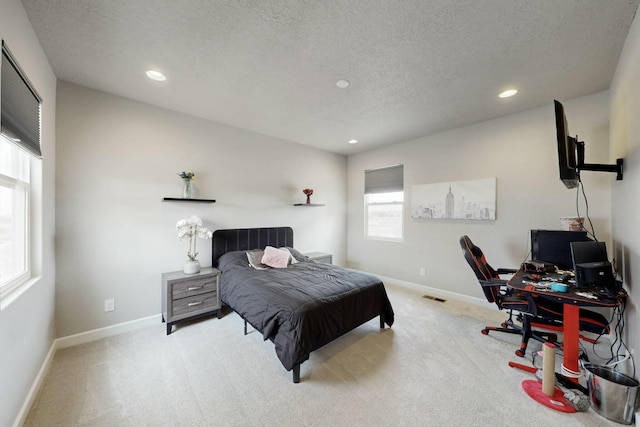 bedroom featuring carpet flooring, visible vents, a textured ceiling, and baseboards