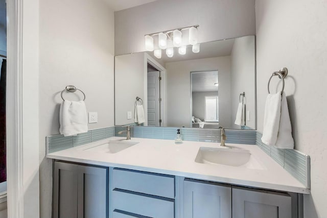 ensuite bathroom featuring double vanity, connected bathroom, and a sink