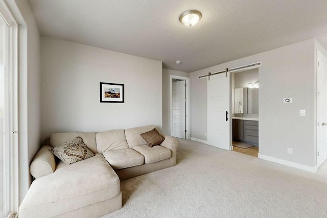 living room with a barn door, baseboards, and light colored carpet