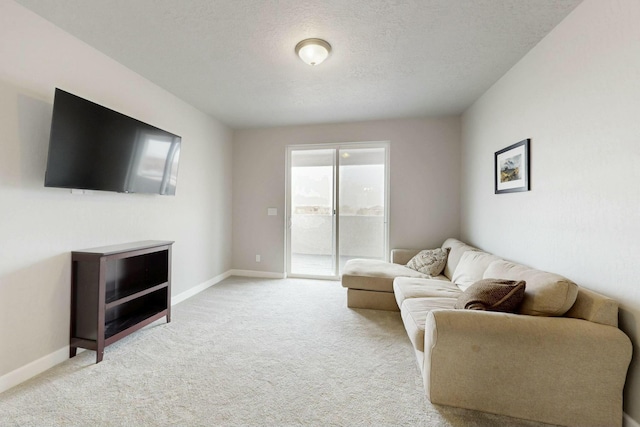 living area featuring light colored carpet, baseboards, and a textured ceiling