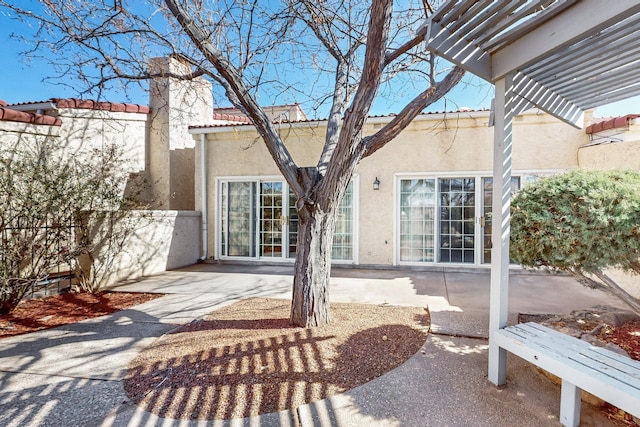 rear view of house featuring a patio, a pergola, a tile roof, and stucco siding