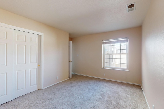 unfurnished bedroom featuring carpet floors, a closet, visible vents, and baseboards