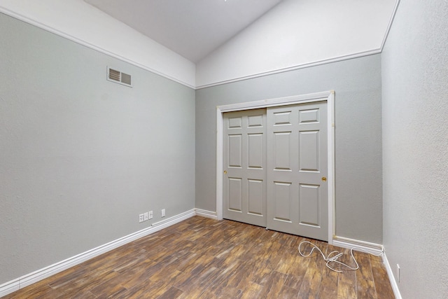 unfurnished bedroom with baseboards, visible vents, lofted ceiling, dark wood-style floors, and a closet