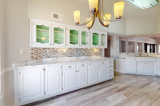 kitchen with light wood-style floors, visible vents, backsplash, and white cabinetry