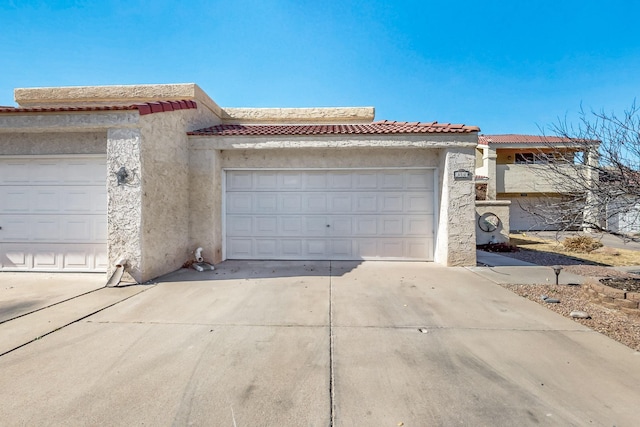 view of front of home featuring a garage, concrete driveway, a tiled roof, and stucco siding