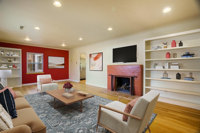 living room featuring a premium fireplace, wood finished floors, and recessed lighting