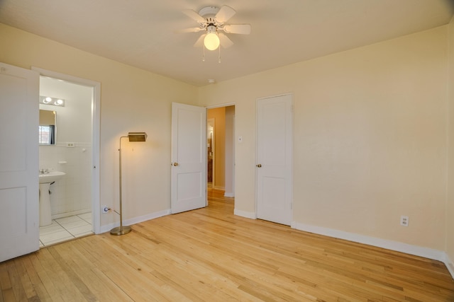 unfurnished bedroom featuring ensuite bathroom, ceiling fan, tile walls, baseboards, and light wood-type flooring